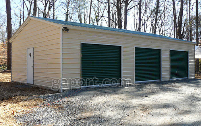 Long metal garage building sample showing three roll up doors and one entry door.