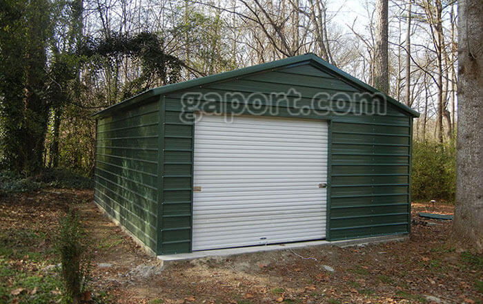 All green metal-garage with garage door offset left and entry door and window in adjacent wall.