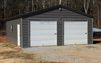 Tidy metal garage displaying use as a workshop with centered large door and entry door.