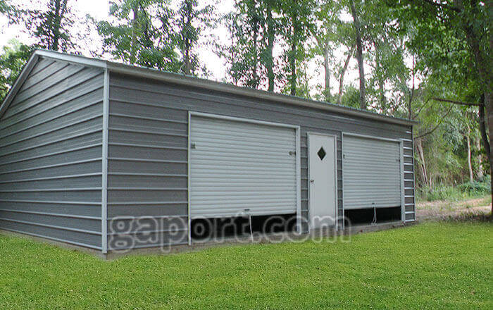Dark grey metal garage with door roll-up doors and an entry door centered between them.