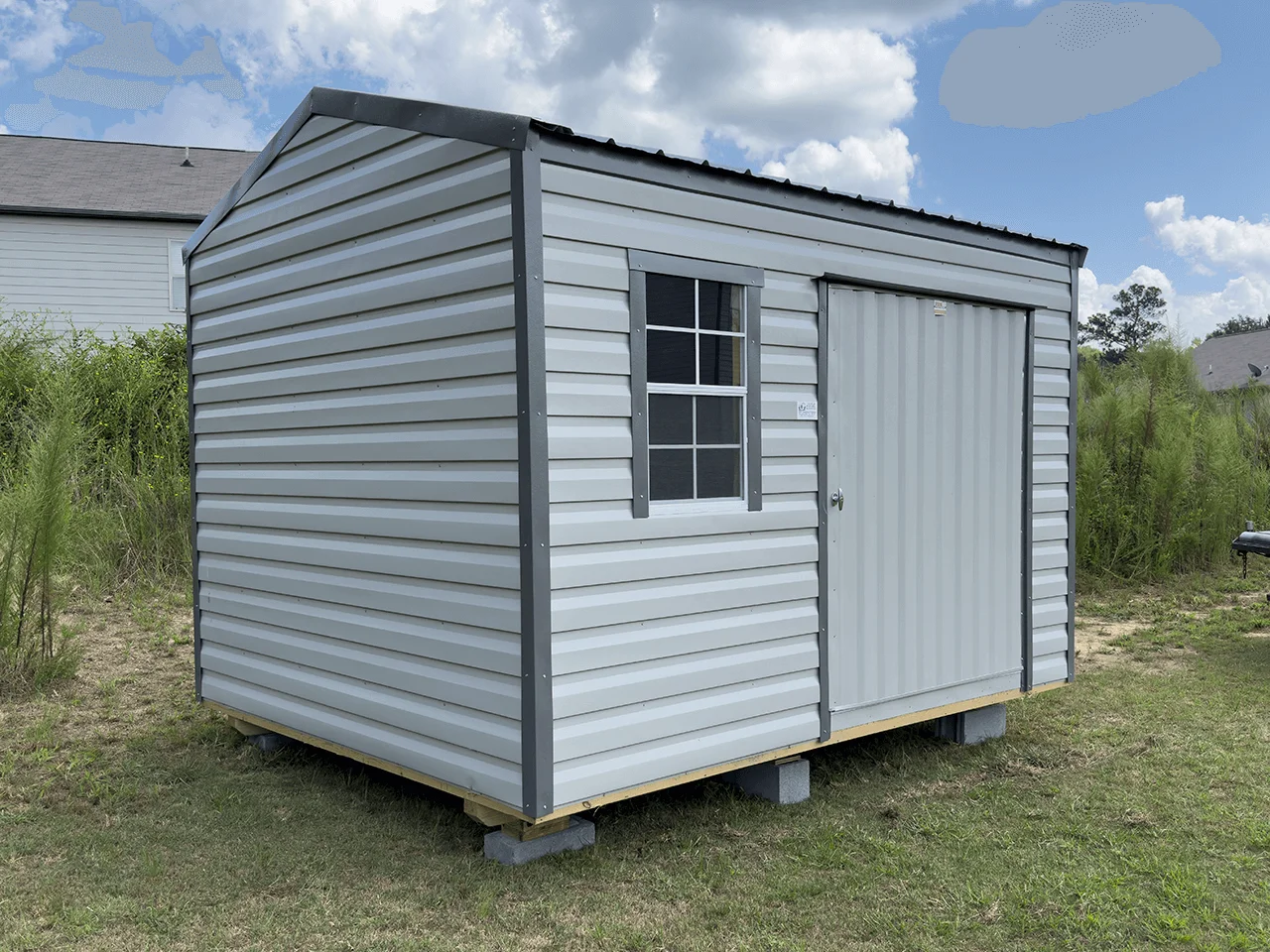 10 x 12 portable shed building with lap siding equipped with wide door for mowers and a window.