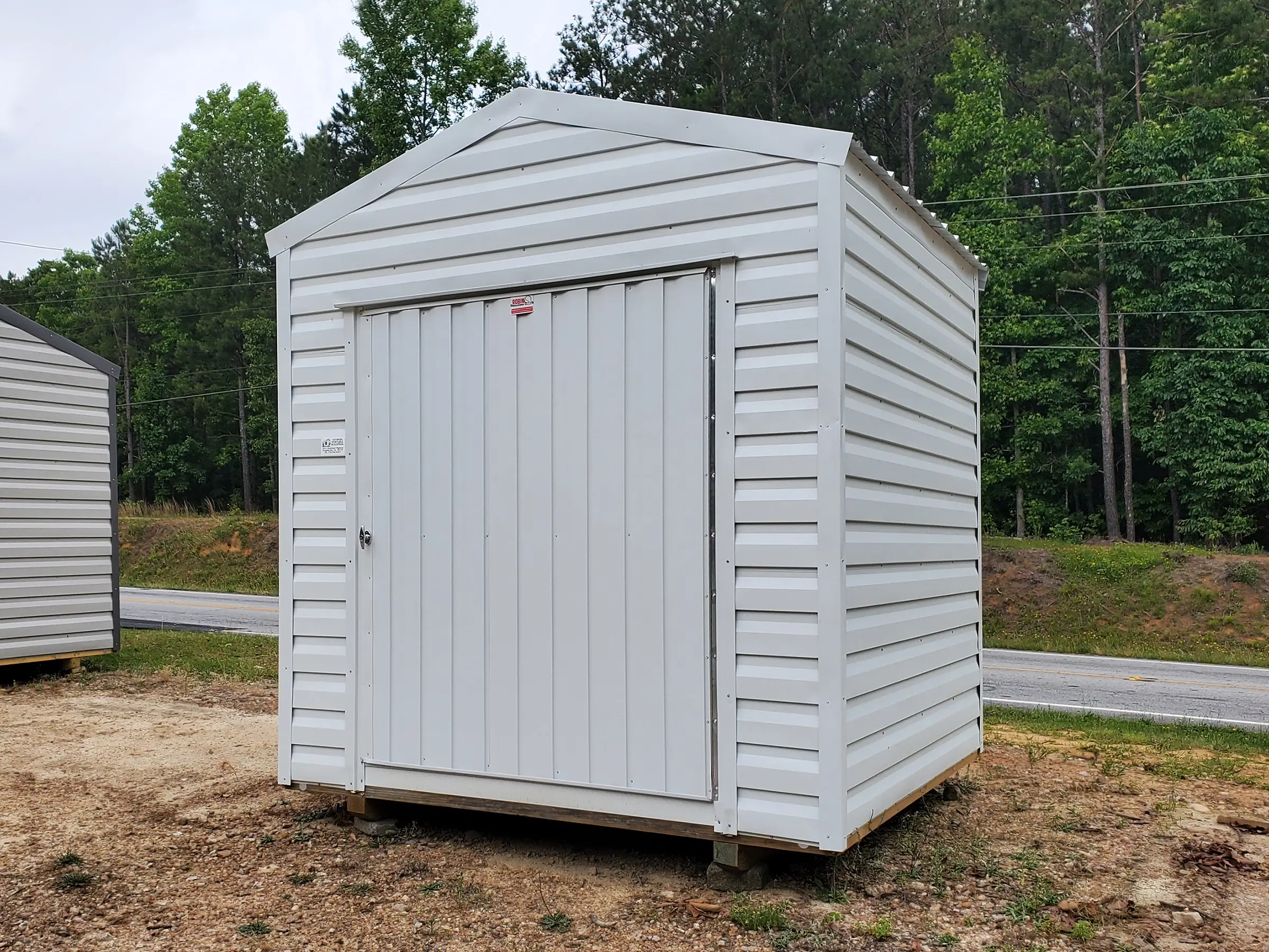 Pictured is a portable building with white siding and white trim in the size 8x8.