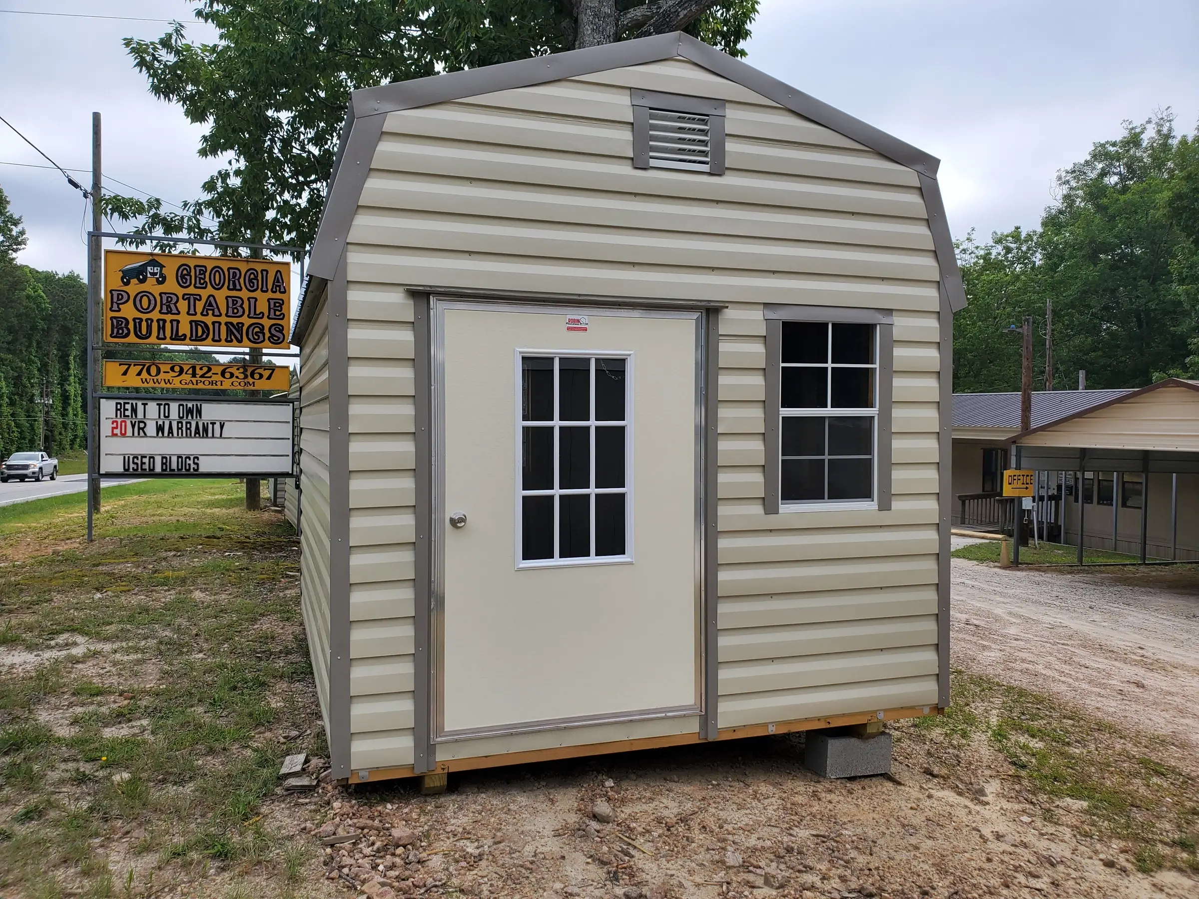 10 by 12 gambrel barn portable structure building with window, vent and nine light door.