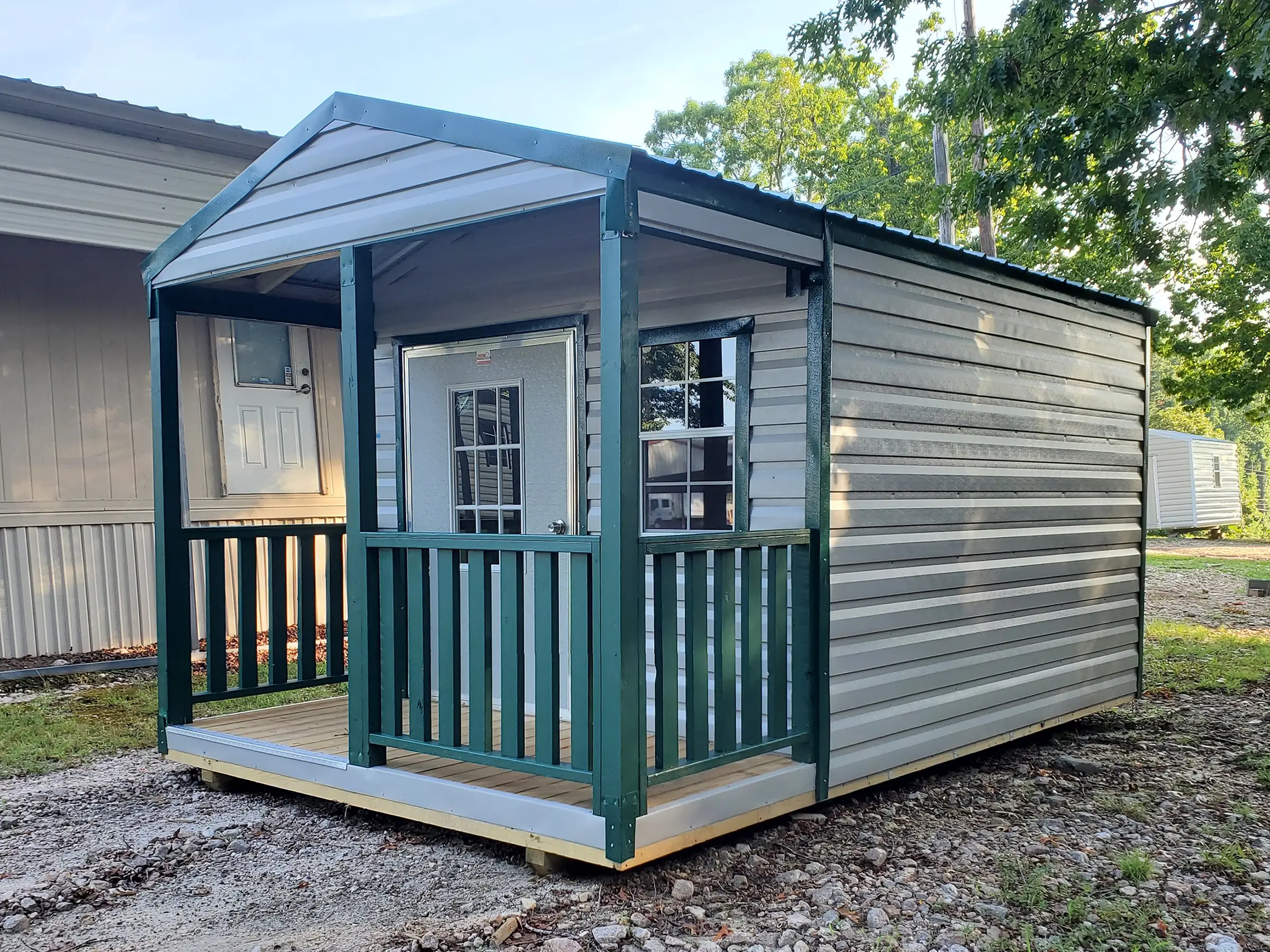 Pictured is a 10x16 portable building with four foot porch on the front with clay siding and green trim