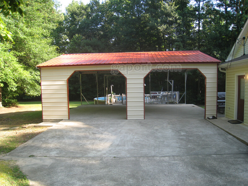 Closer front view of attractive two car side entry metal carport with barn red trim.