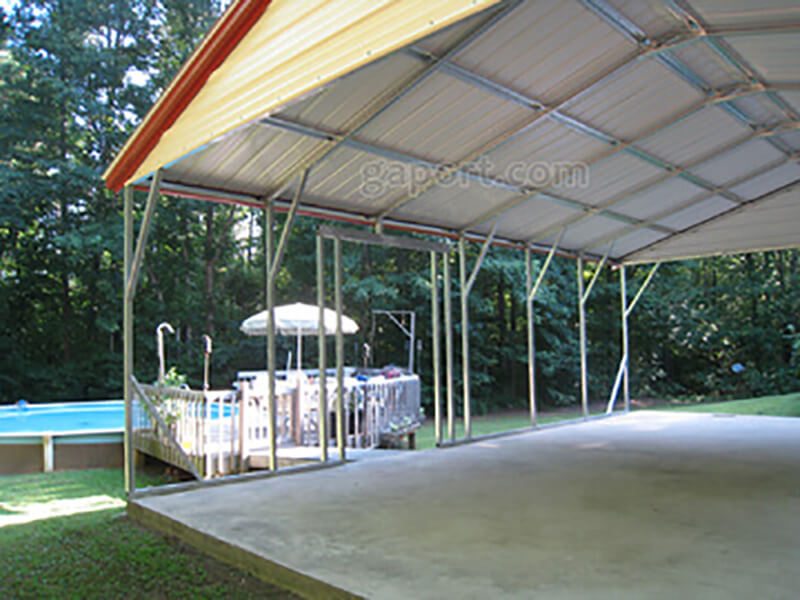 Interior view of side entry metal carport looking out through an opening for the entrance to the pool.
