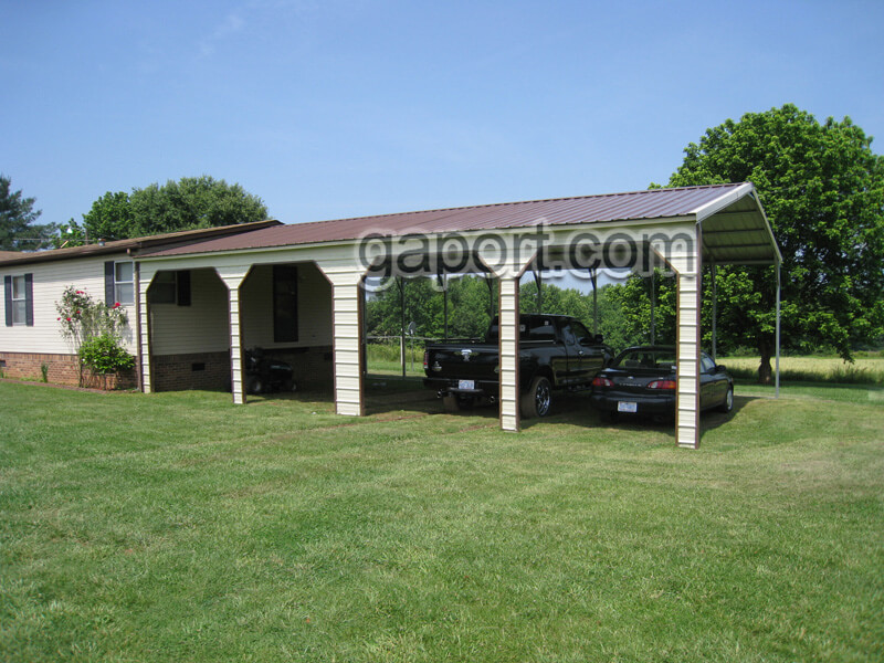Angled view of nice four car side entry steel carport where the whole house is seen in the background.