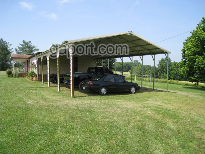 Angled view of attractive four car side entry metal carport where the whole house is seen in the background.